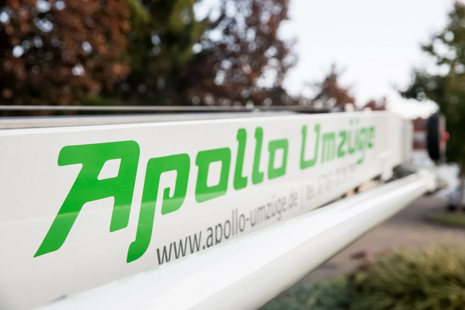 Nahaufnahme eines weißen Umzugswagens mit grünem Schriftzug Apollo Umzüge.