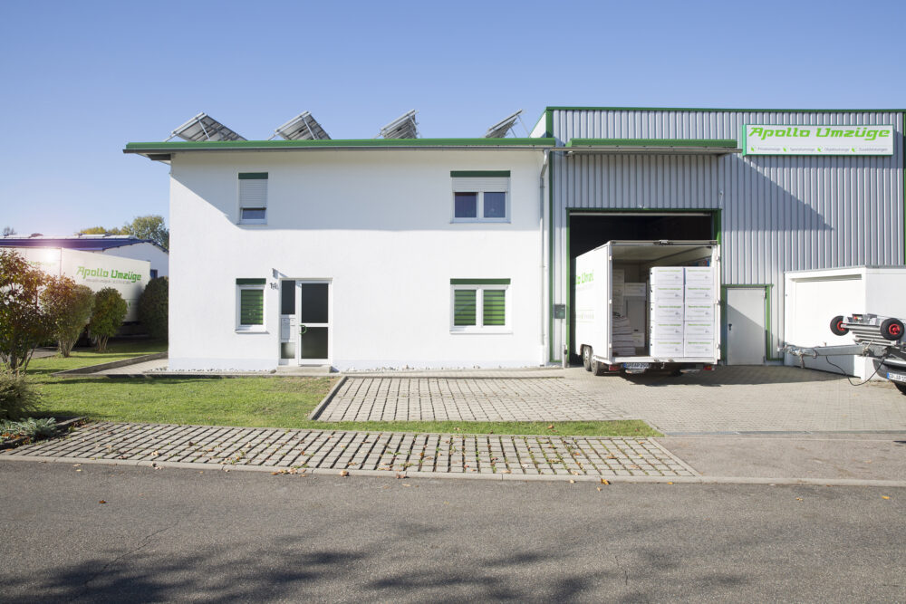 Industriegebäude mit LKW-Laderampe und angrenzendem Bürogebäude bei klarem Himmel.