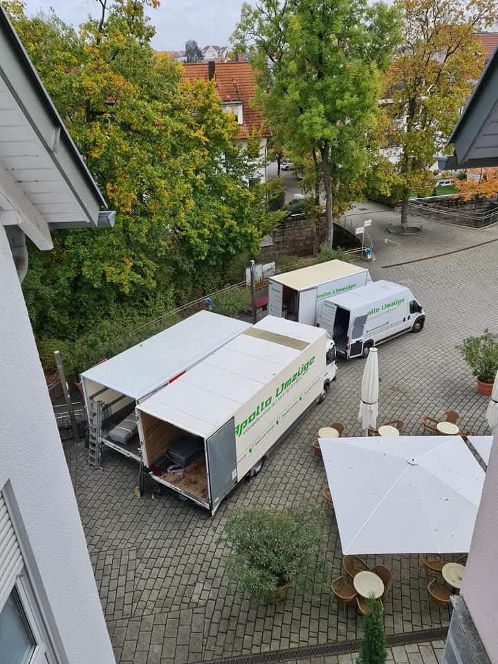 Blick von oben auf zwei Lieferwagen und einen gepflasterten Innenhof mit Bäumen und Sitzgelegenheiten.