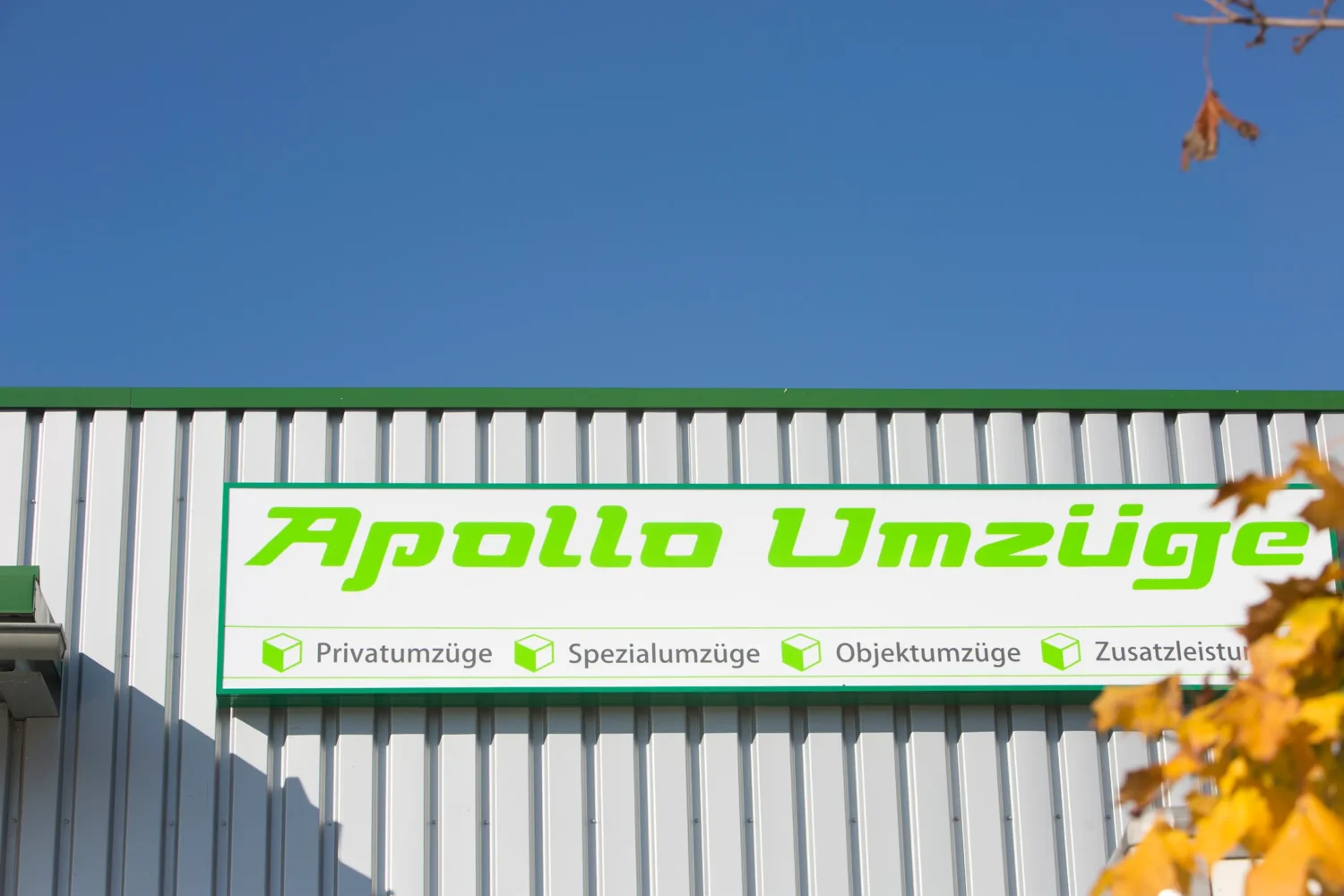 Firmenschild von Apollo Umzüge an einer Gebäudewand vor blauem Himmel.