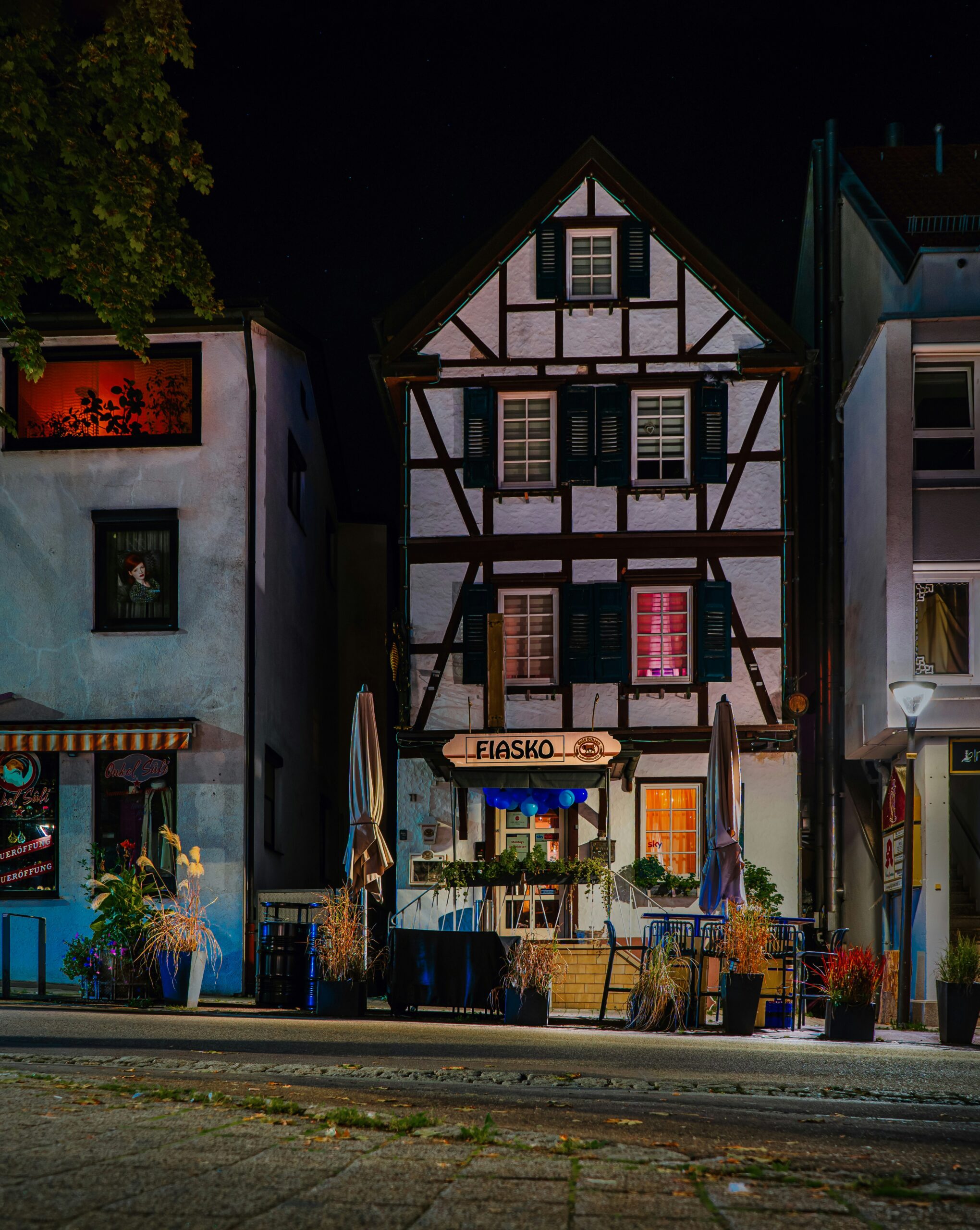 Fachwerkhaus mit beleuchtetem Restaurant bei Nacht in einer Stadt.