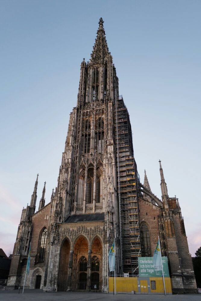 Gotische Kathedrale mit hohem Turm vor blauem Himmel.